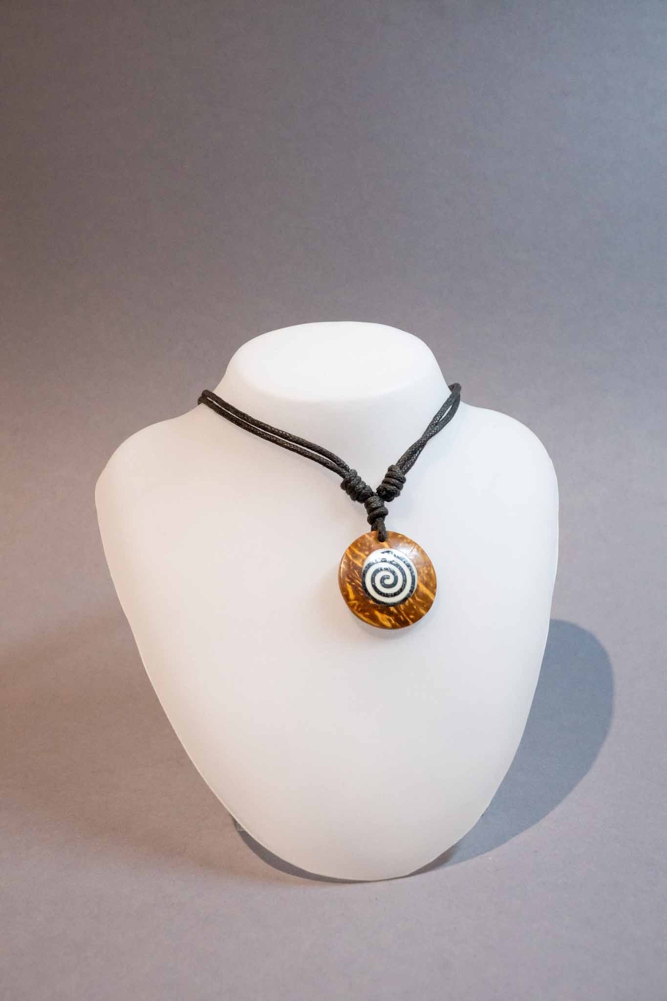 Hellbrauner Holzanhaenger mit Schwarz-Weisser aufgemalter Spirale